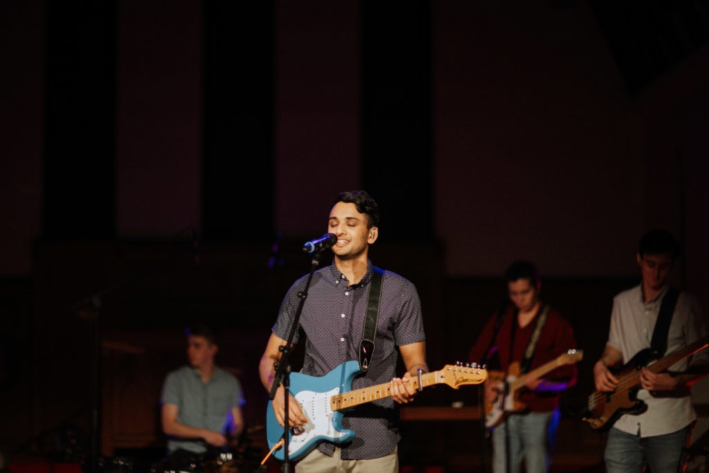 young man playing a guitar in band